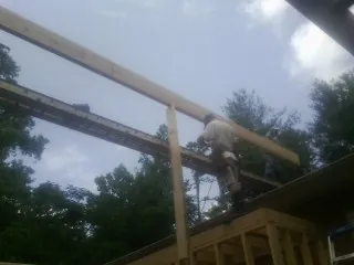 Carpenter setting a ridge beam over a new addition frame — Ice Dam Removal by Roofing Brothers in Doswell