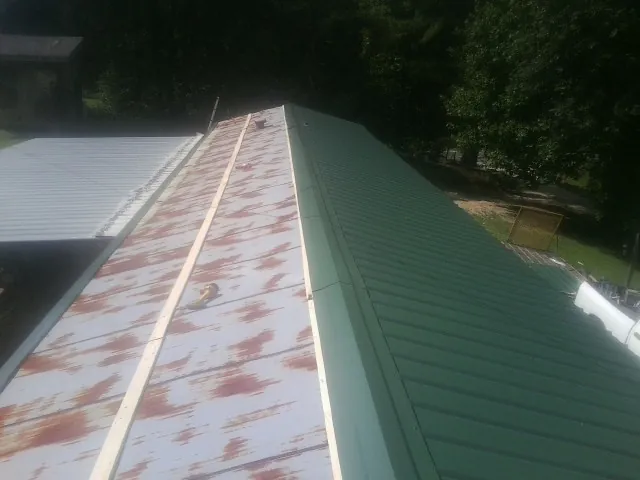 Old rusted panels beside newly installed green metal roofing — Wind Damage Roof Repair by Roofing Brothers in Doswell