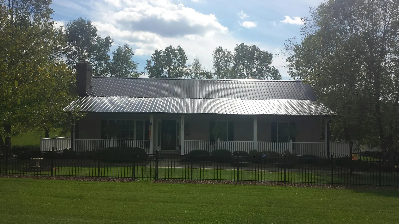 Gray metal roof on a brick ranch with a full width front porch — Gutter Guard Installation work by our crew in Doswell