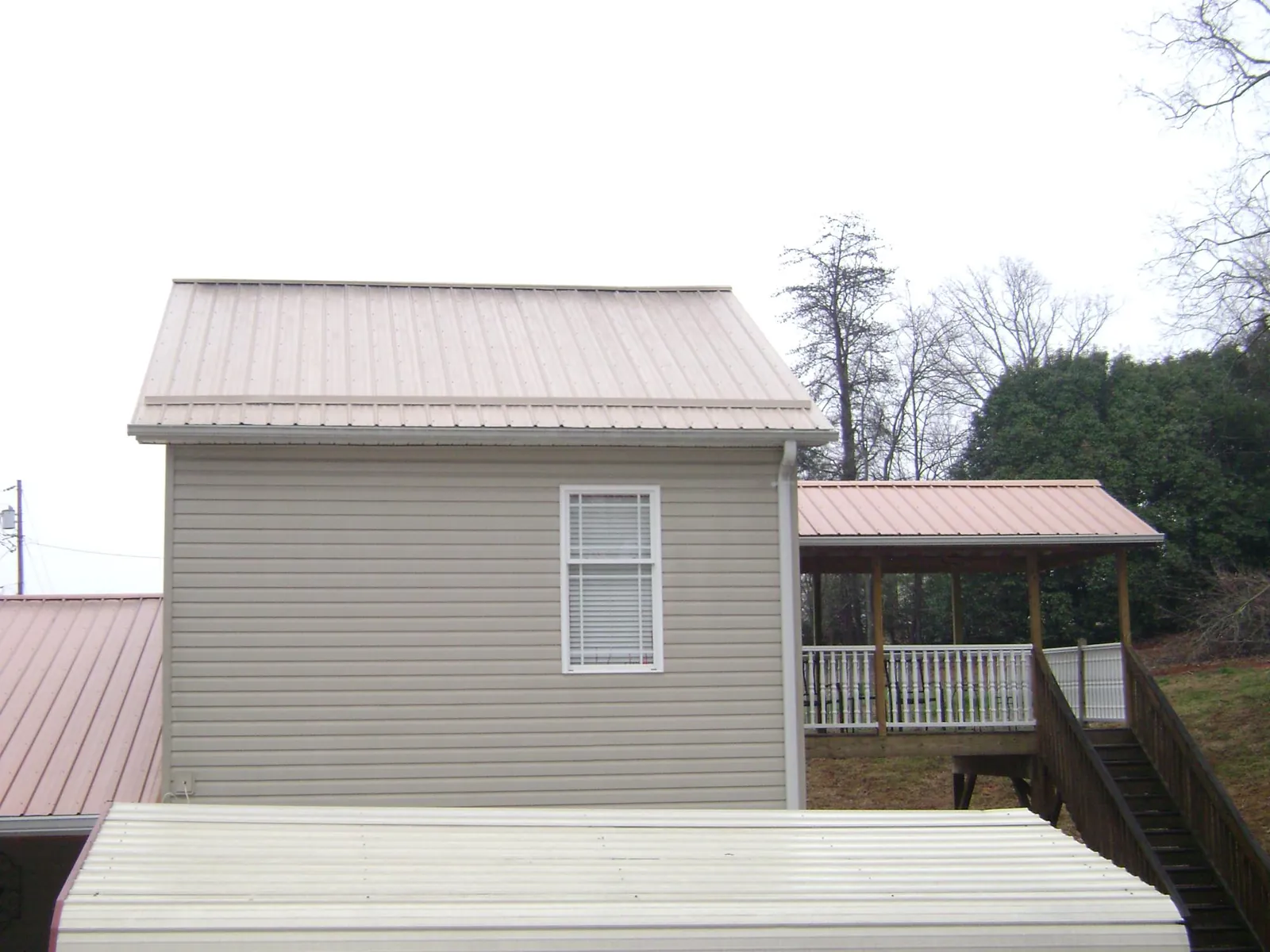 Tan metal roofs on a two story addition and attached porch, from a Roof Replacement job in Doswell